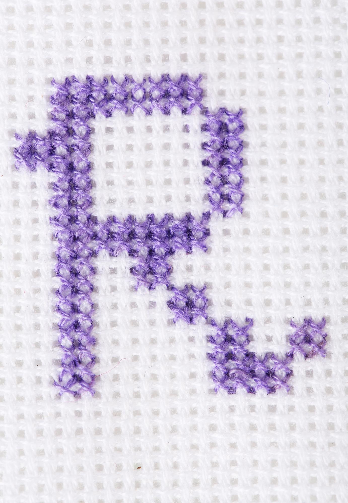Mały haftowany monogram na lnianej tkaninie